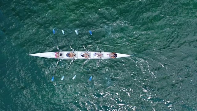 Aerial drone bird's eye view video of sport canoe operated by team of young women in emerald open ocean sea