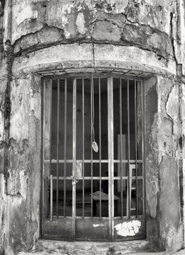 monochrome image of rusted metal bars on the doorway of an old abandoned derelict building with cracked walls