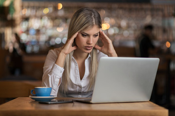 Frustrated businesswoman reading a problematic e-mail on a computer in a cafe