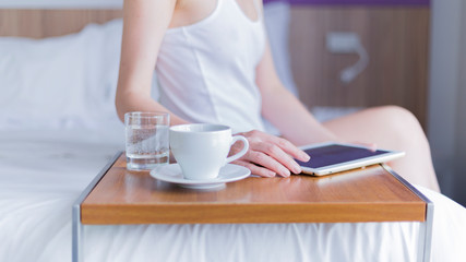 young woman having breakfast and reading a tablet
