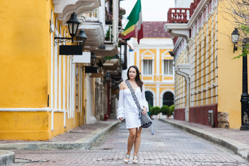 Beautiful woman on white dress walking alone at the streets of the colonial walled city of Cartagena de Indias