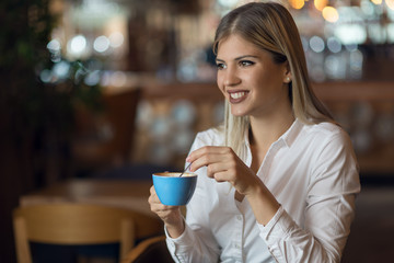 Happy woman enjoying in a cup of coffee and day dreaming
