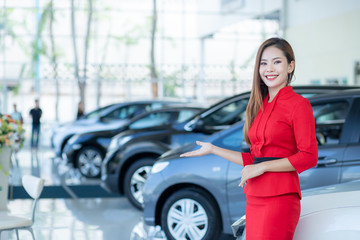 Fototapeta na wymiar Beautiful Asian woman or car salesman Stand holding a new car remote key in the showroom, Cars For Sale.