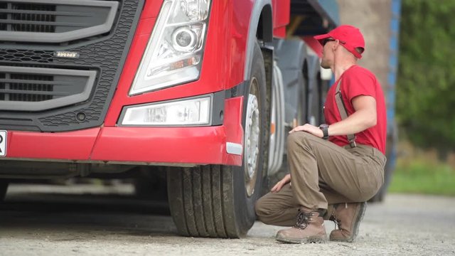 Caucasian Truck Driver Making Quick Tires Check. Transportation Industry.