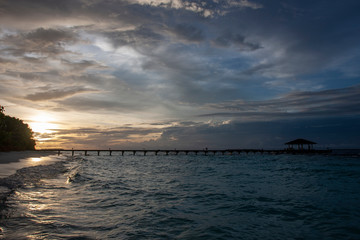 Fototapeta na wymiar Silhouette of the long pier, bridge, on the background of a sunset on Maldives Islands. Night landscape. 