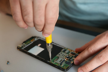 Technician repairing mobile phone at table, closeup