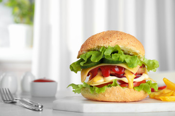 Board with tasty burger on table. Space for text