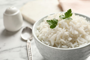 Bowl of tasty cooked rice with parsley served on table, closeup. Space for text
