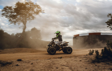 A child rides a quad bike through the mud. ATV rider rides on the dirt