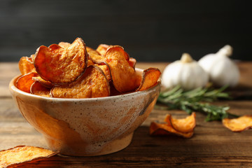 Delicious sweet potato chips in bowl on table. Space for text