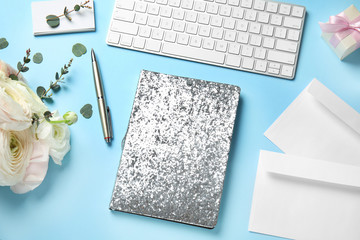 Composition with glittering notebook, keyboard and spring flowers on color background