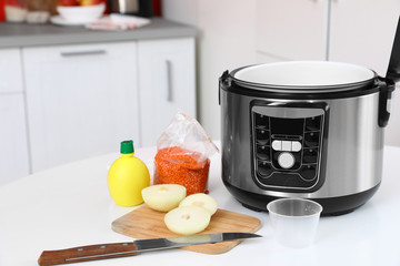 New modern multi cooker and products on table in kitchen. Space for text