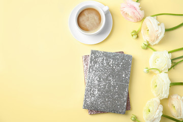 Flat lay composition with notebooks, coffee and flowers on color background. Space for text