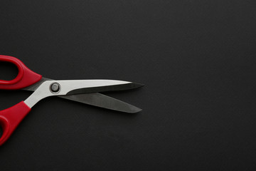 Pair of sharp scissors on dark background, top view. Space for text