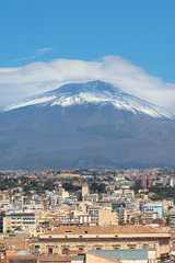 Famous Mount Etna volcano in Sicily, Italy captured on vertical picture with houses belonging to city Catania located at the foot of the mountain. Popular tourist spot