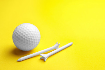 Golf ball and tees on color background, space for text. Sport equipment