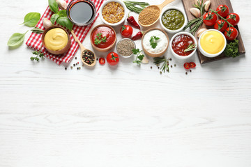 Flat lay composition with different sauces and space for text on white wooden background