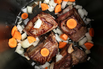 Top view of delicious pork ribs with vegetables in modern multi cooker, closeup