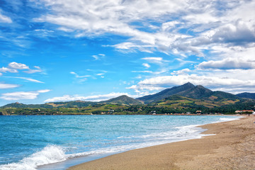 Beautiful deserted beach and mountains on the background. Argeles sur Mer, Roussillon, Pyrenees Orientales, France - obrazy, fototapety, plakaty