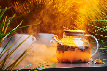 Ceylon tea in a transparent teapot on a smoky gray background with warm lighting and decorated with...