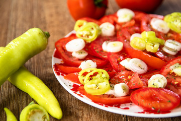 Salad with fresh tomatoes, young onion and hot paprika on wooden table