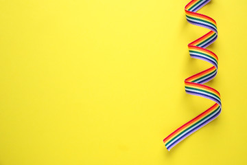 Top view of rainbow ribbon on yellow background, space for text. Gay symbol