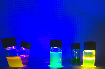 Multiple colourful close up photochemical reaction in glass vial under blue UV light in a dark...