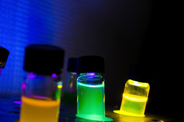 Multiple colourful close up light induced photochemical reaction in glass vial under blue UV light...