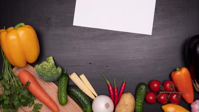 Fresh vegetables frame with blank sheet of white paper on the kitchen table. View from top. Space fo text. Stop motion.