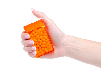 Dragee in orange container in hand on white background isolation