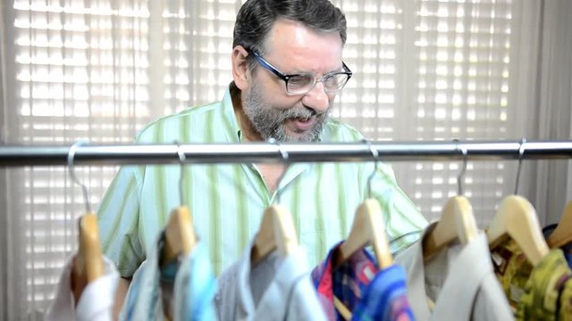Inconsiderate saleswoman taps a bearded mature buyer on the shoulder near clothing rack. As a result, he goes away from the clothes shop.