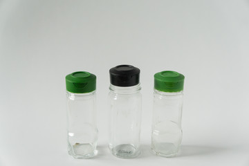 3 Multiple reusable spice seasoning jars; Green & black sprinkle lid tops for recycling campaign programs; Isolated kitchen item on horizontal white background; Blank empty copyspace; text copy room.