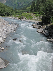 torrential glacier milk river on a sunny day making its way to the valley