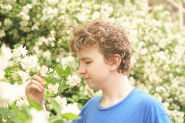 Obraz premium young man stands among the flowers and enjoys summer and flowering
