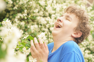Obraz premium young man stands among the flowers and enjoys summer and flowering