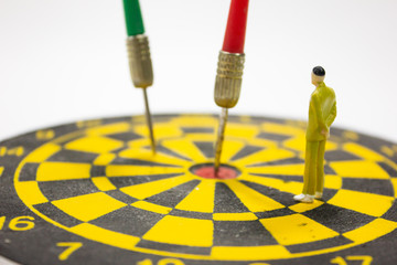 Miniature businessman stand and dart hit on center of dartboard. business success concept.