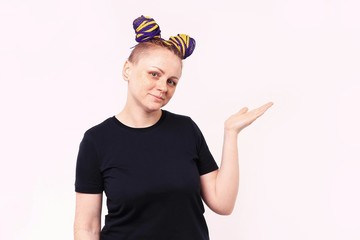 Woman in casual wear shows her palm to side and smiling. The woman has dreadlocks on her head, freckles on her face. White background.