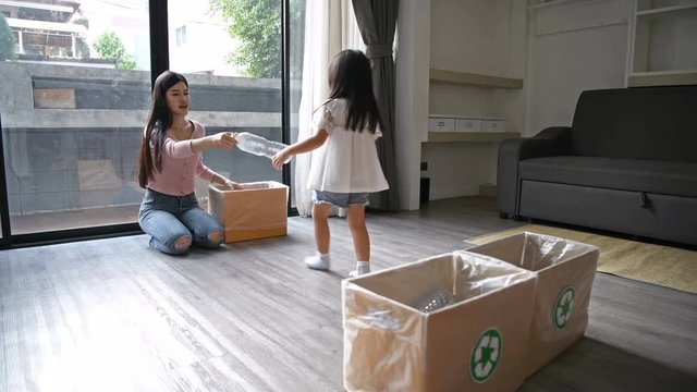 The concept of global conservation. Daughter is helping mothers to separate the garbage in the house.