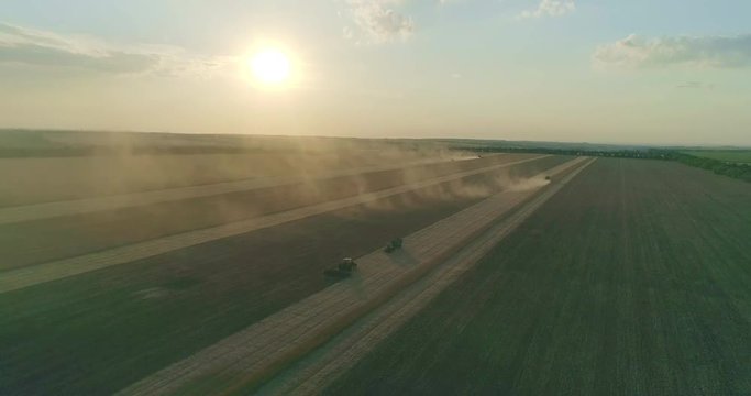 Farm machinery is gathering rhy crop at the sunset