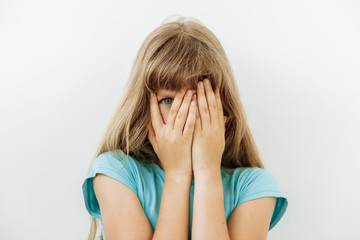 Fear,Shame and shy emotion. Portrait of  9 year girl against white background