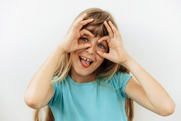 Fototapeta premium Making face,funny foolishes portrait of 9 year girl, against white background.