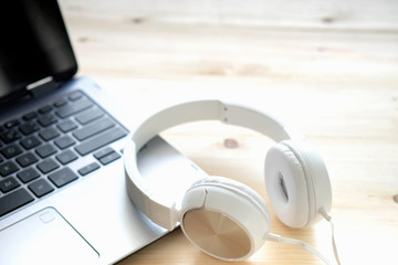 White headphone and laptop computer on wooden background