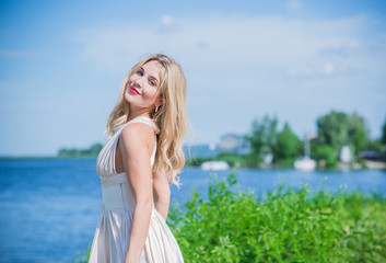 Fototapeta premium Nice blonde lady at nature. Woman in flying silk white dress at outdoor, relax time 