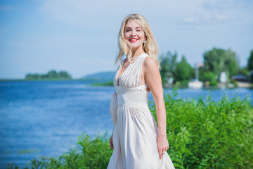 Fototapeta premium Nice blonde lady at nature. Woman in flying silk white dress at outdoor, relax time 