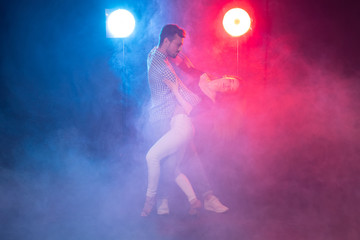 Social dance, bachata, kizomba, zouk and tango concept - Man hugs woman while dancing over lights