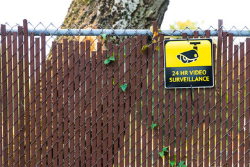 24 hour video surveillance sign on a fence
