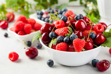 Berries closeup colorful assorted mix of strawberry, blueberry, raspberry and sweet cherry on a white table.
