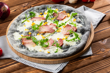 Tasty pizza with ham, corn, rucola and cheese.