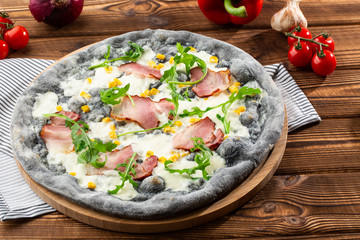 Tasty pizza with ham, corn, rucola and cheese.