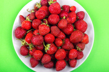 Strawberries on a plate on a green background